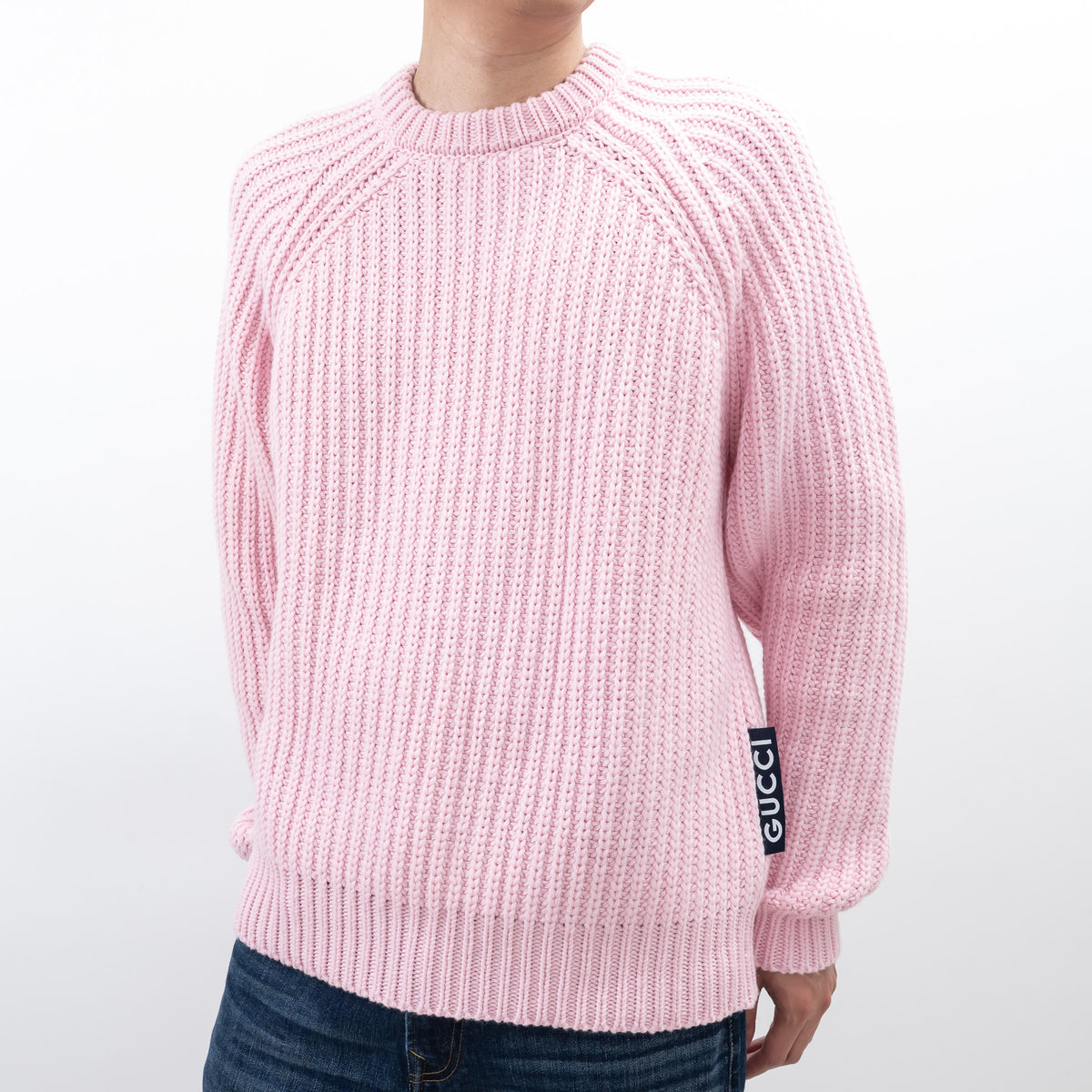 Pink sweater with Gucci logo on sleeve against a white background