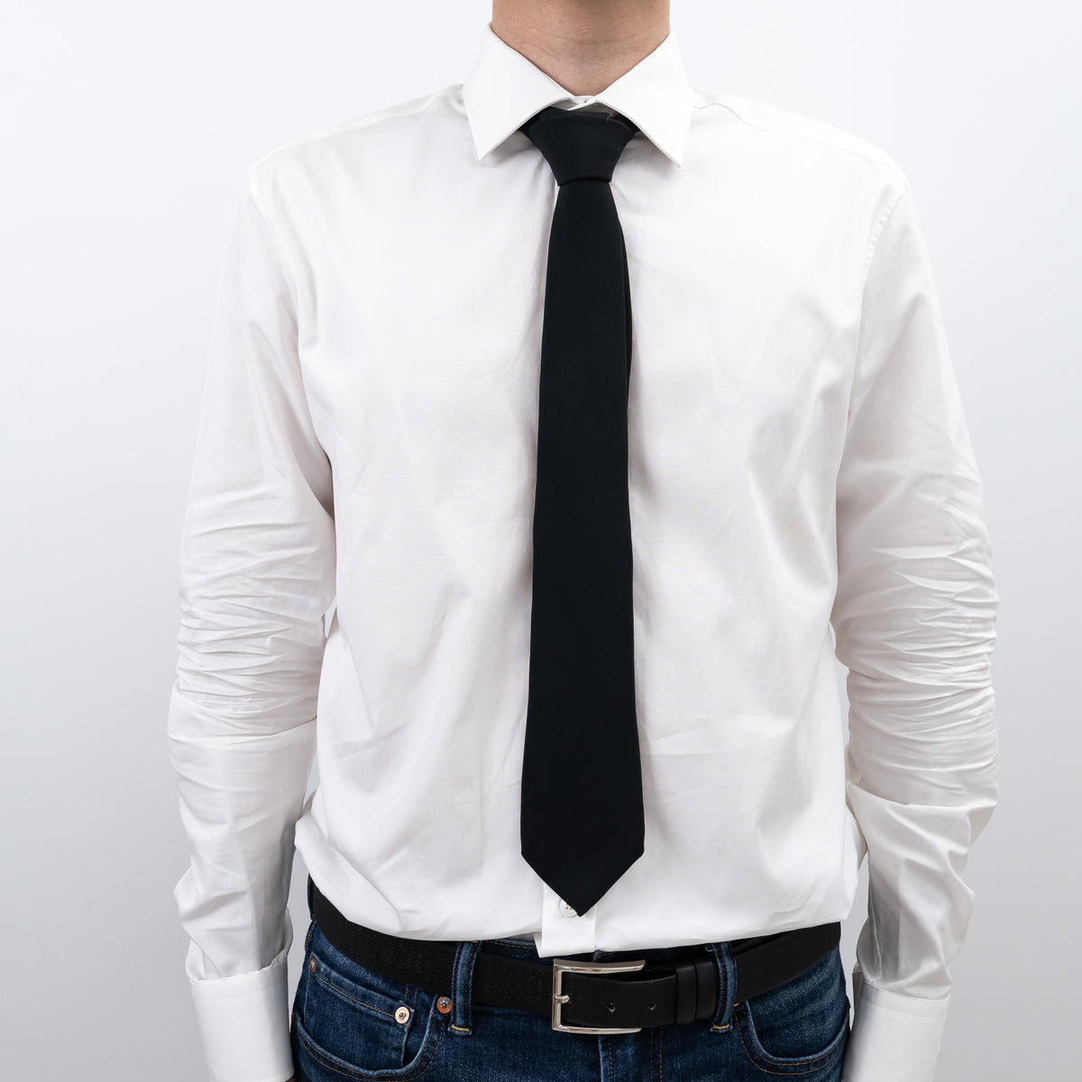 White dress shirt with a Gucci  black tie and jeans on a plain background