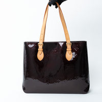 Louis Vuitton Burgundy patent leather handbag with beige handles on a white background