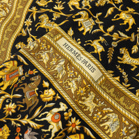 Close up of Hermes Black and Gold Silk Chasse En Inde Scarf with motifs of Hunters, Birds, Lions, Tigers, Elephants, Gazelles, Horses, and Flowers 