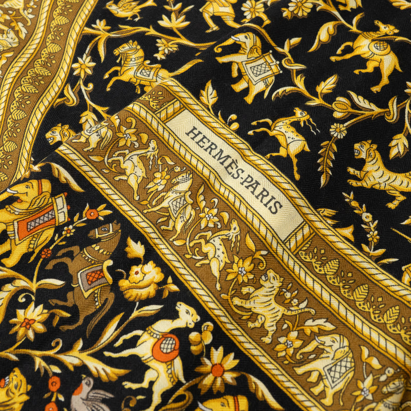 Close up of Hermes Black and Gold Silk Chasse En Inde Scarf with motifs of Hunters, Birds, Lions, Tigers, Elephants, Gazelles, Horses, and Flowers 