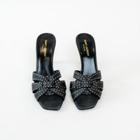 Black studded sandals with bow detail on a white background