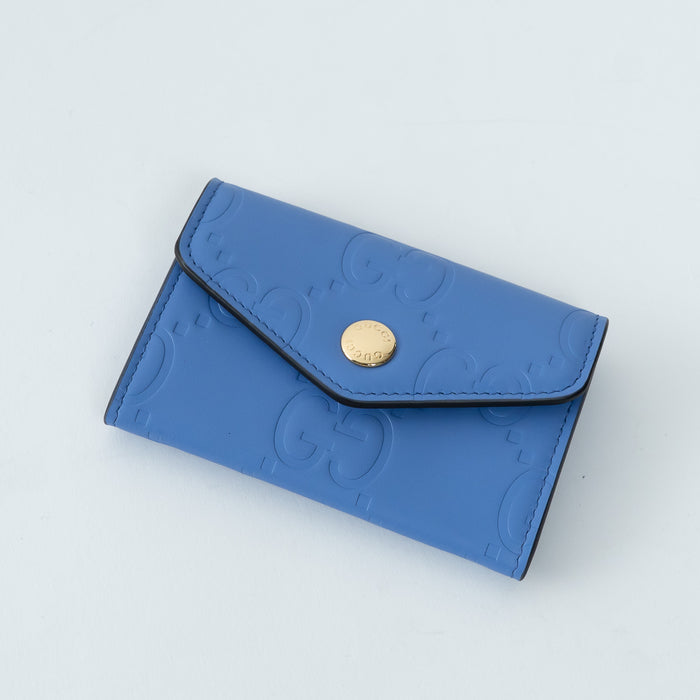 Blue wallet with a gold button on a light gray background