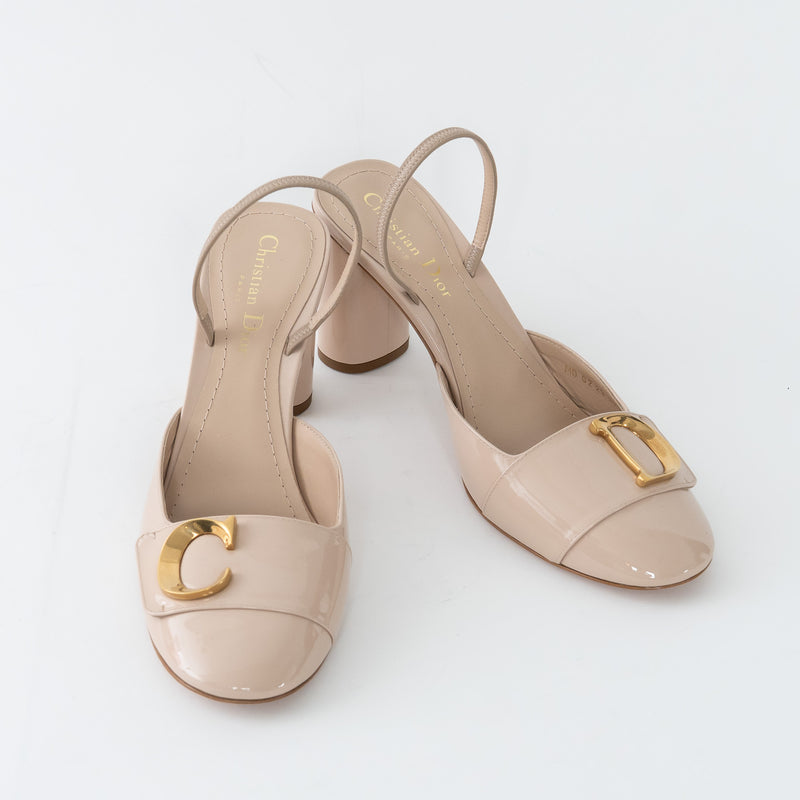 Pair of beige high-heeled shoes with gold accents on a white background