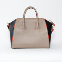 Multicolored handbag with beige, black, and orange sections on a white background