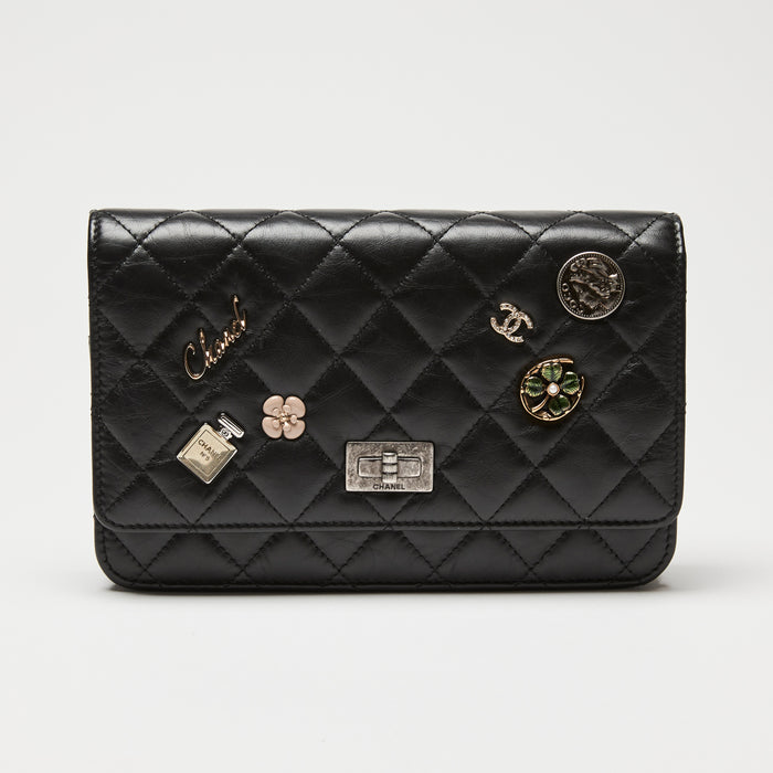 Black quilted Chanel wallet on chain with various Chanel logos and charms