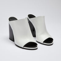 Excellent Pre-Loved White Leather and Black Enameled Block Heel Peep Toe Mules with Oversized Logo Etched on Backside of Heels. (side)