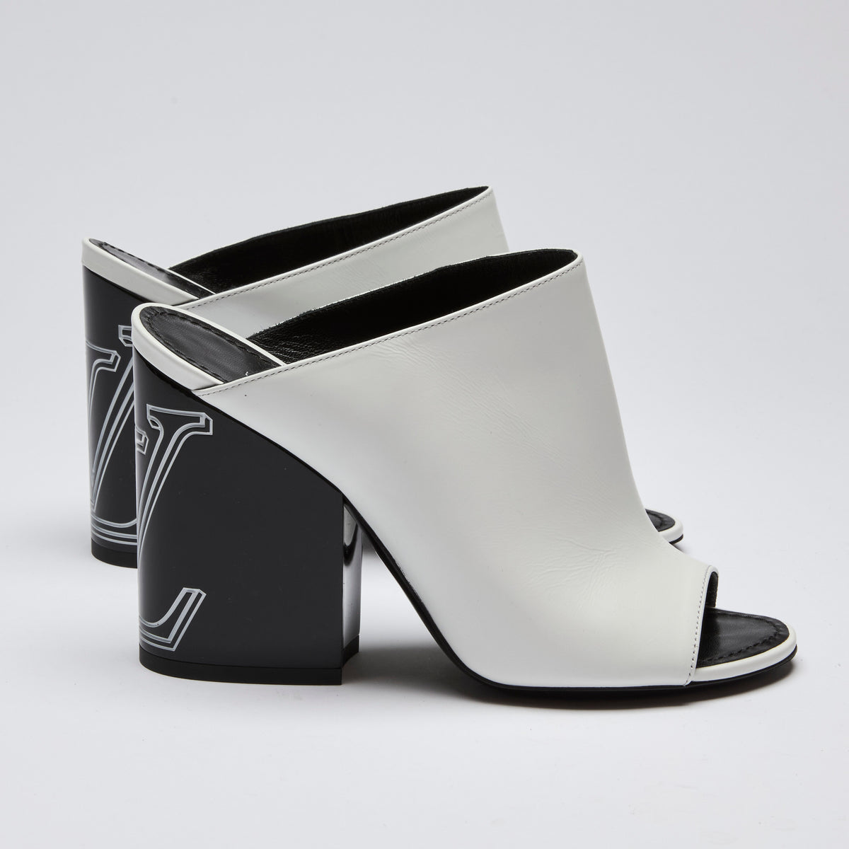 Excellent Pre-Loved White Leather and Black Enameled Block Heel Peep Toe Mules with Oversized Logo Etched on Backside of Heels. (side)